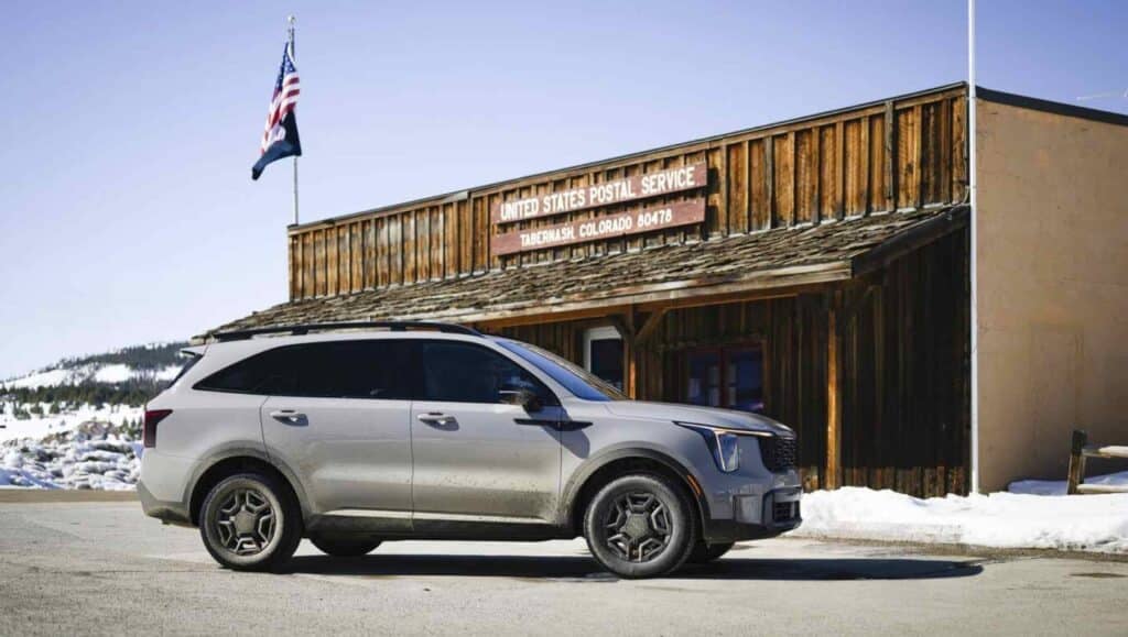 A side view of a 2026 Kia Sorento in front of a rural post office