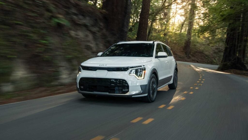 A 2025 Kia Niro EV in white driving on a forest road
