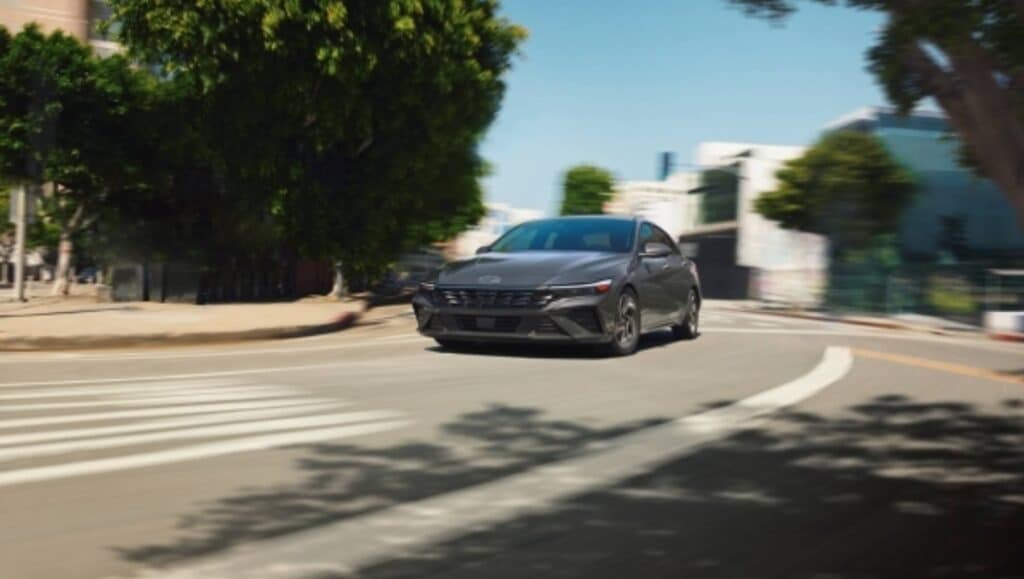 A blue Hyundai Elantra driving down a street