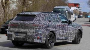 Rear 3/4 view of a a camouflaged BMW iX5 M70 prototype