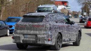 Rear 3/4 view of a a camouflaged BMW iX5 M70 prototype