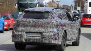 Rear 3/4 view of a a camouflaged BMW iX5 M70 prototype