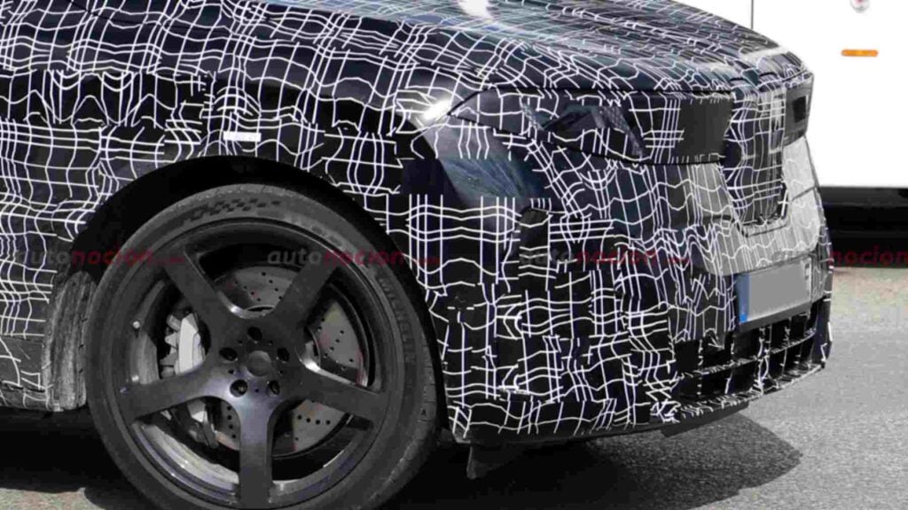 Side front view of a camouflaged BMW iX5 M70 prototype