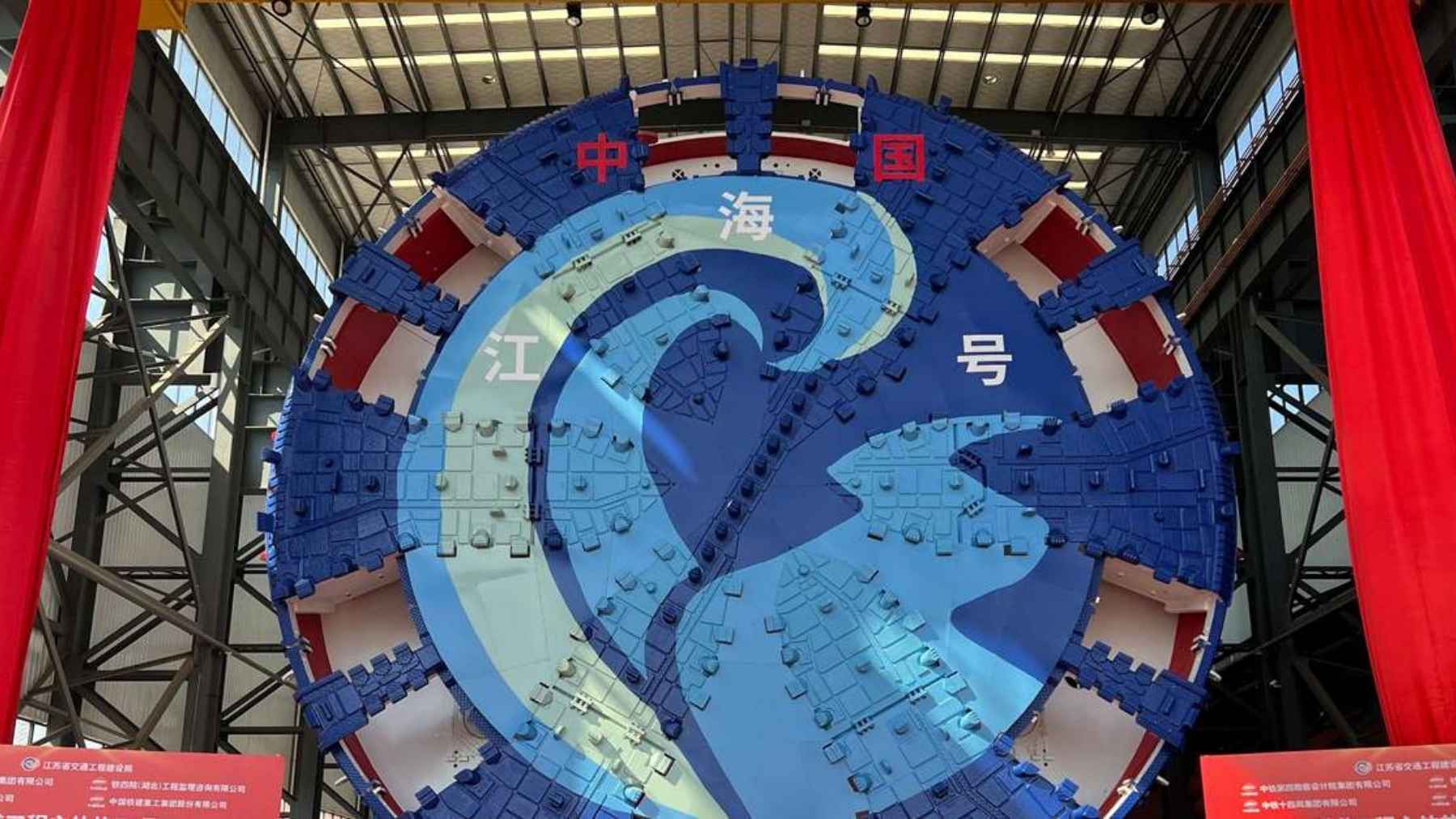 China built a 5,000-ton boring machine with a cutter head 54 feet across, five stories of spinning steel, and pointed it straight under the Yangtze to carve a six-lane highway through soft riverbed where a bridge couldn’t go
