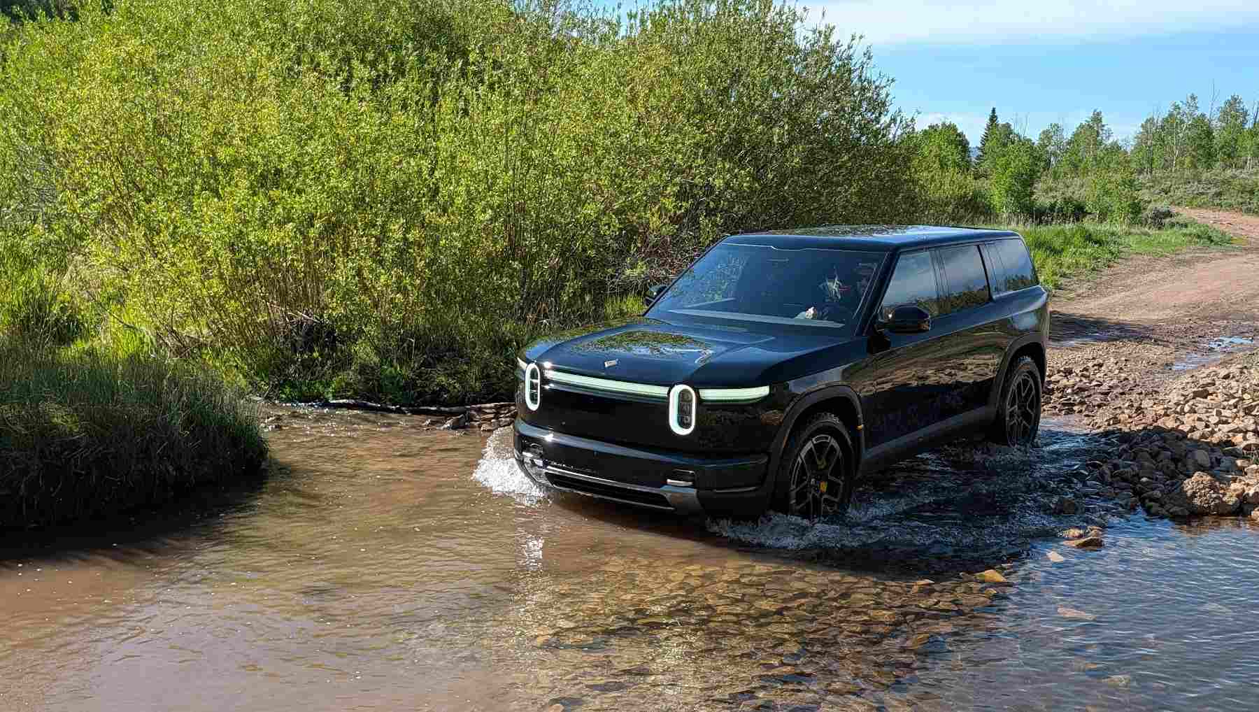 A Rivian R2 crossing a stream