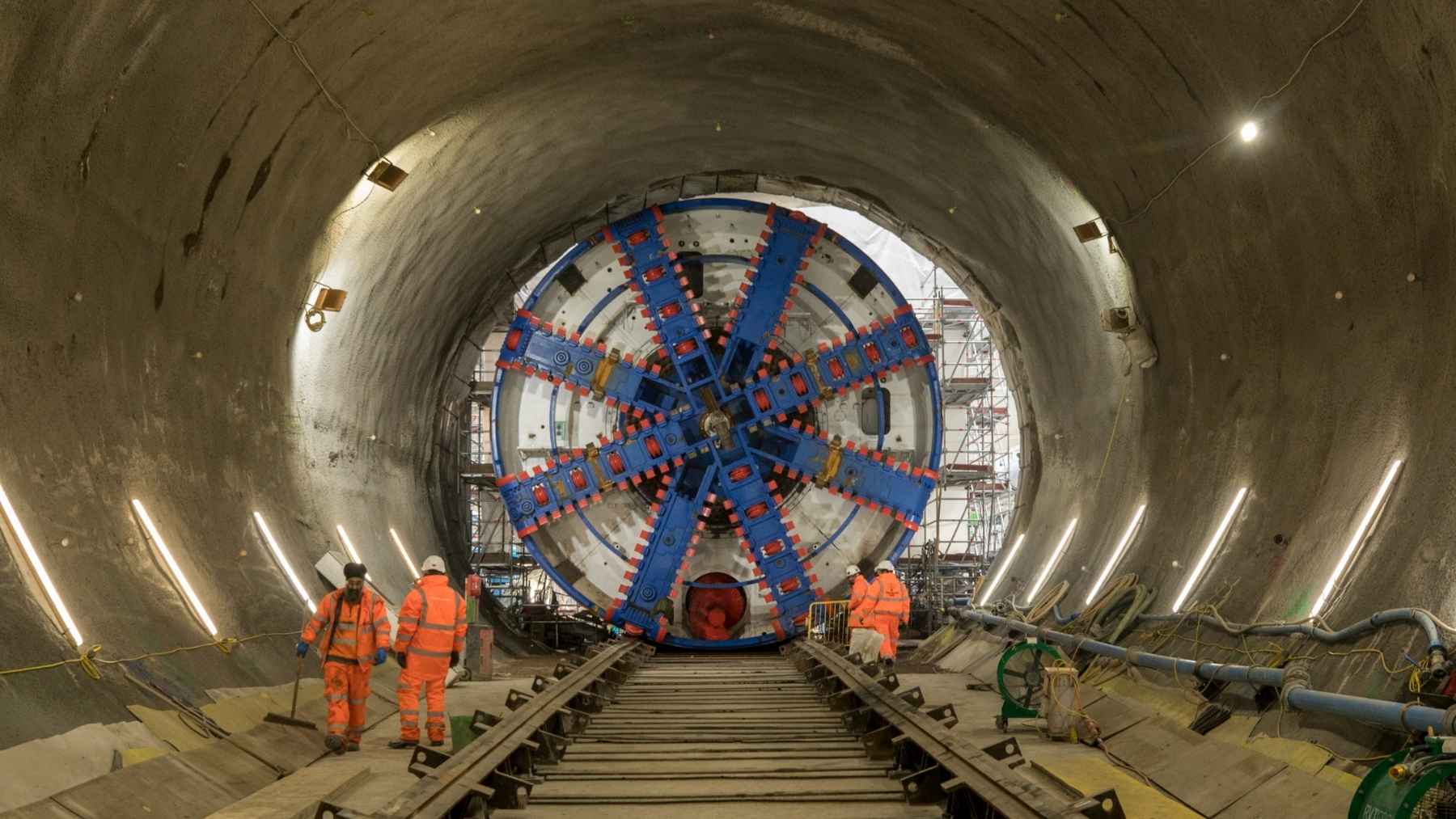 The hero shot is always the 650-foot German machine, and back up the tube out of frame there is a shed full of compressors pushing brine at 26 below into the dirt until the sand turns into a 6.5-foot wall of ice — and it does not get to stop until the concrete is in