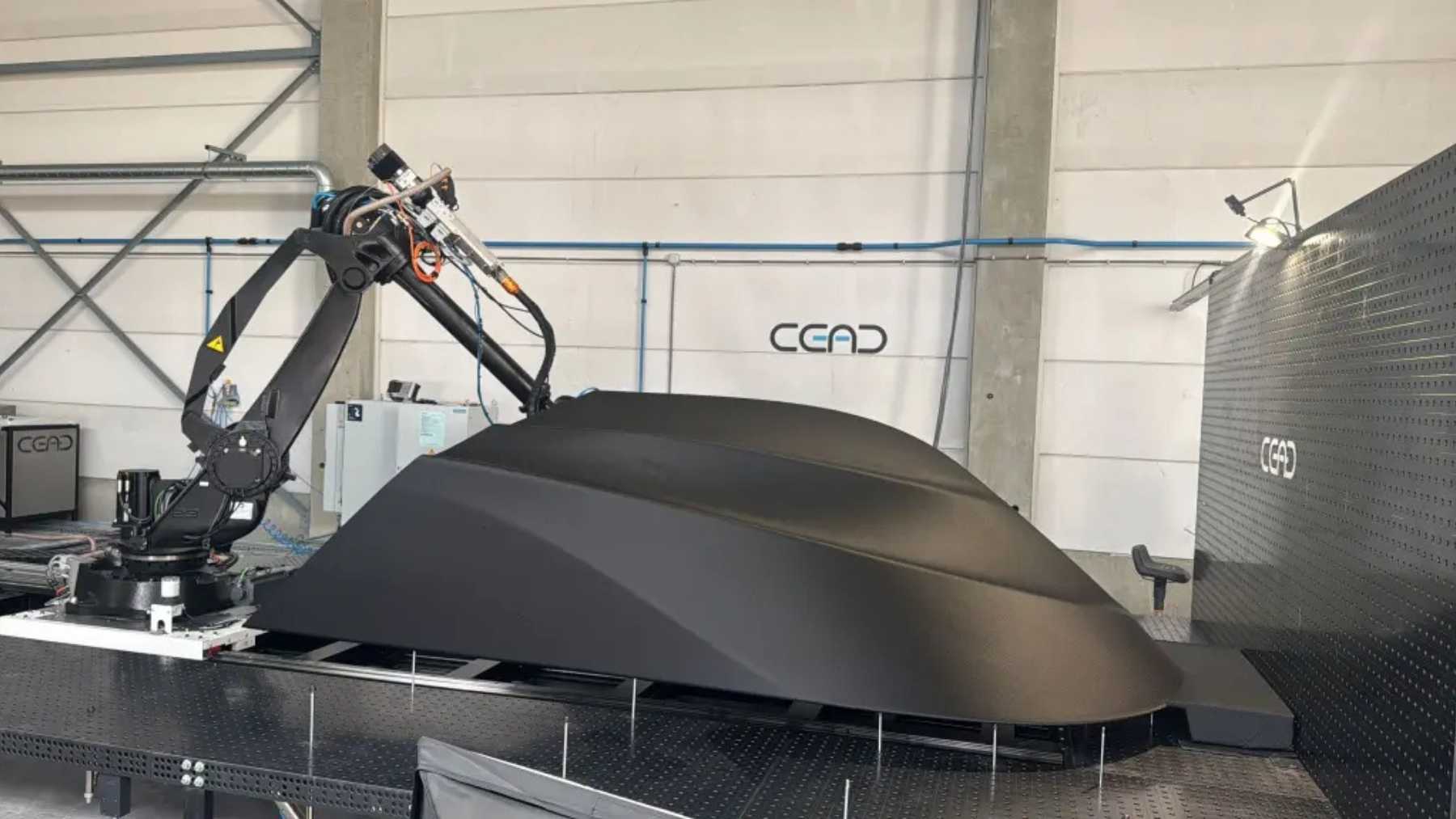 A Florida shop that was printing furniture four years ago now runs eight robot arms that lay boat hulls down one bead at a time with no mold, turned out a 40-foot half-submerged hull in nine days, and the drone boat it just unveiled has no length, no customer and no mission.
