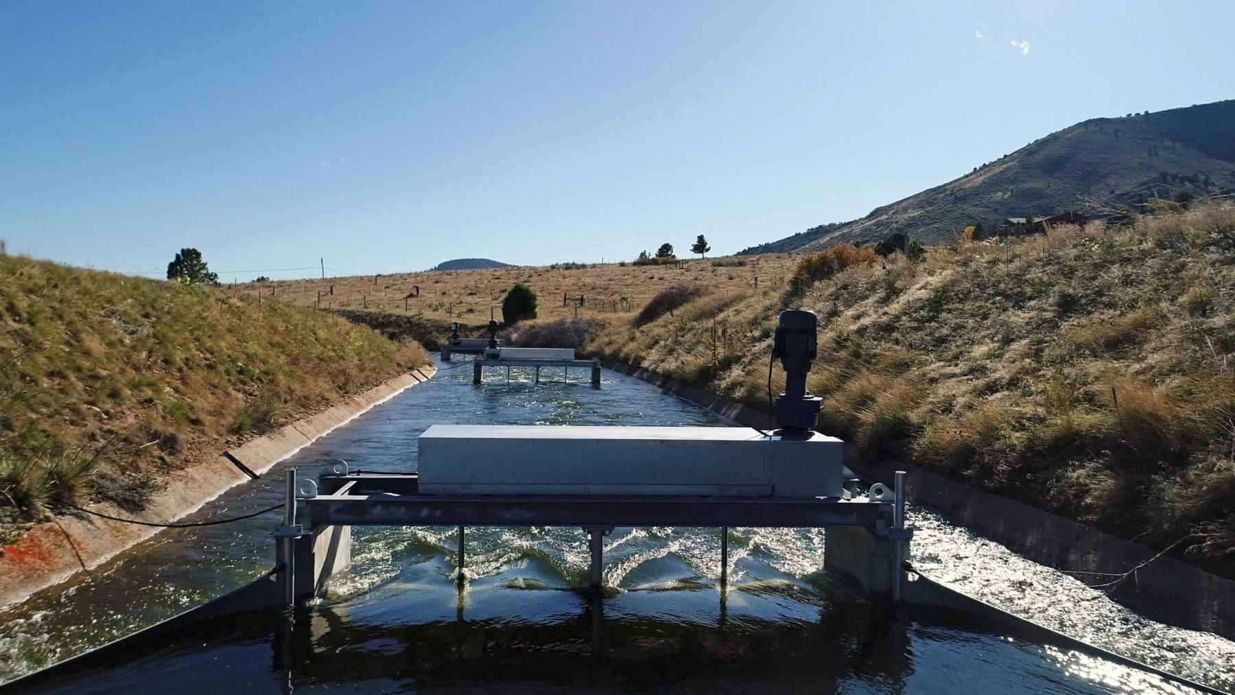 Four turbines sit in a Denver irrigation canal, dropped in cassette-style so nobody ever has to shut the water off to the farms downstream, and each one makes about what three home EV chargers pull, on a canal network 11,800 miles long