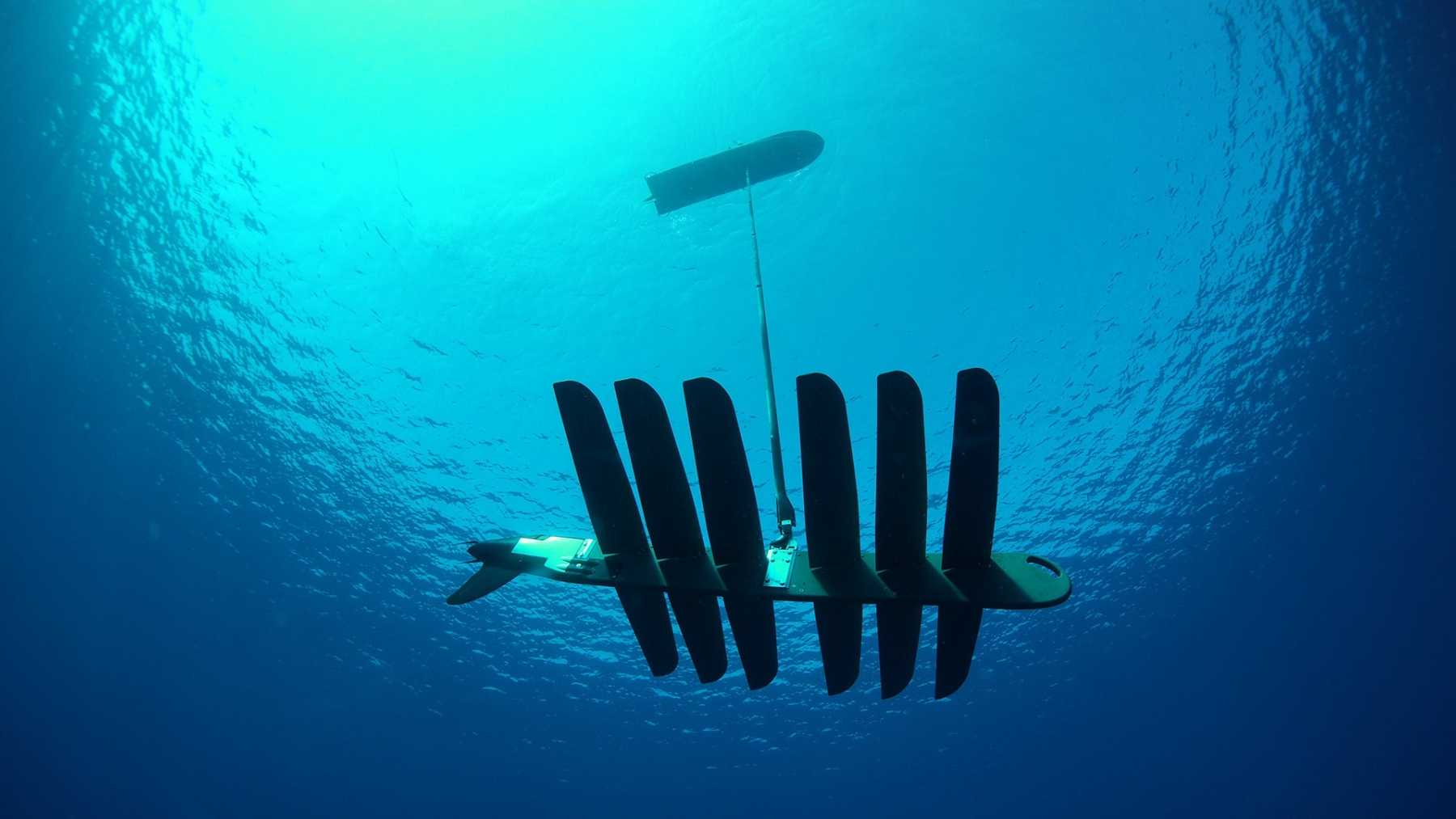 Japan is taking 20 American wave-powered drones through a $25 million US Air Force deal — 18-foot surfboard machines that stay at sea for a year on swell and sun, with no engine and no fuel tank — to help figure out where things that fall over water actually land