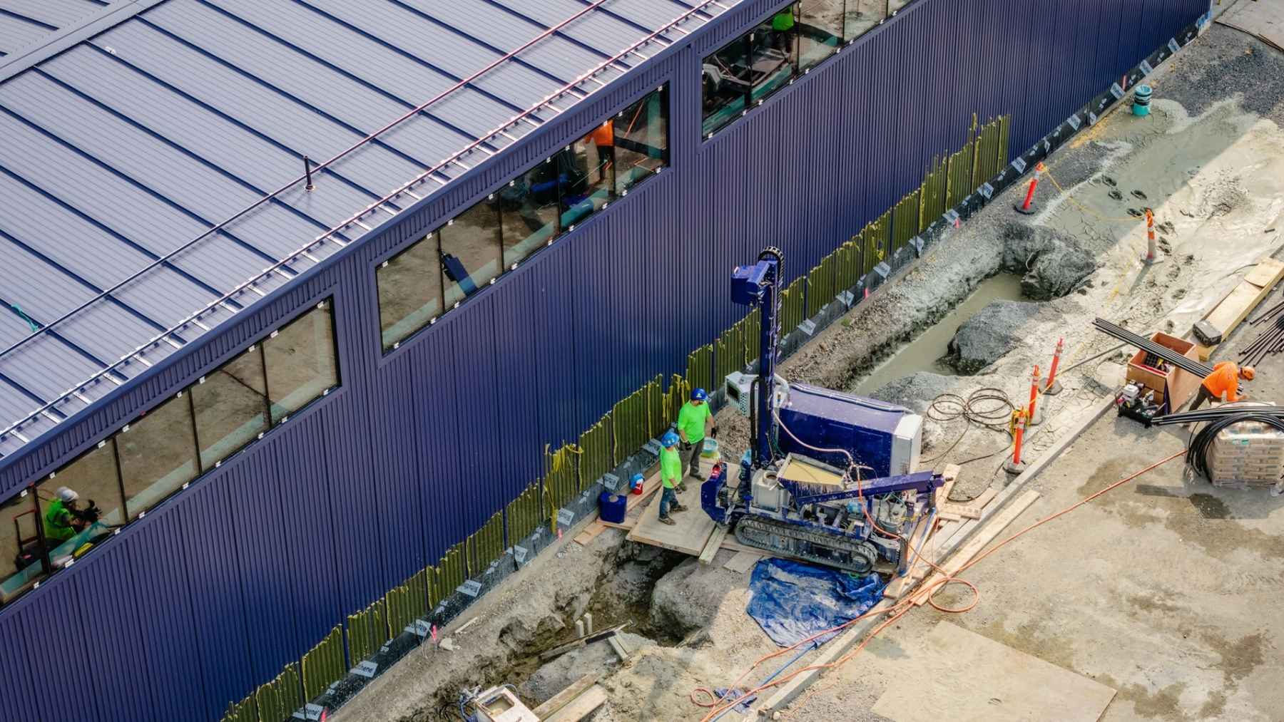 A drilling rig that takes up one parking space cut seven geothermal boreholes outside a Boston office with water sprayed at 10,000 psi instead of a metal bit, and its drill pipe never came back out, because the pipe itself becomes the heat exchanger