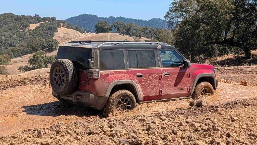 A rear 3/4 view of a red 2026 Jeep Recon fording water
