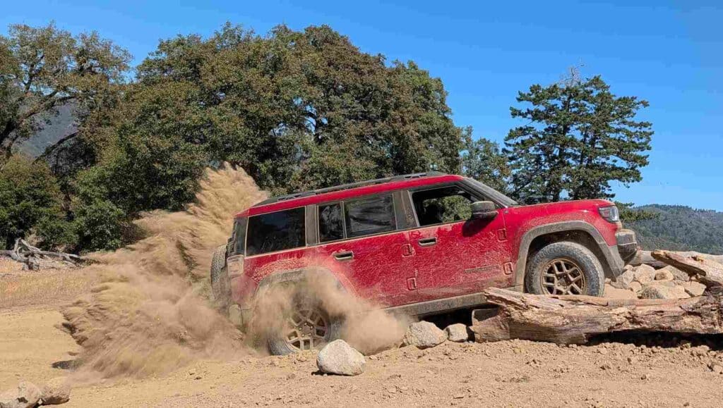 Side view of a red 2026 Jeep Recon kicking up dust
