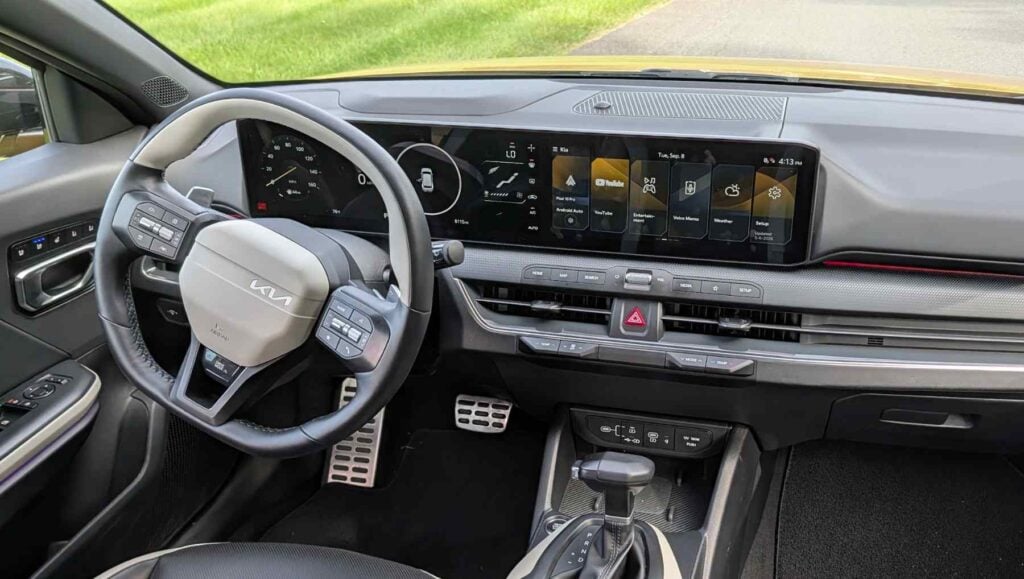 The dash and wheel of a gold 2026 Kia K4