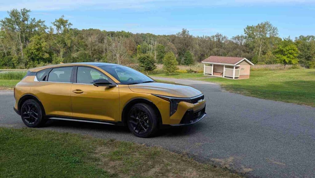 A gold 2026 Kia K4 on a road in a park