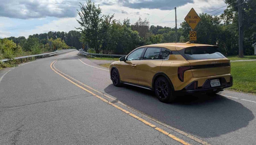 A rear view of of a gold 2026 Kia K4 on the road