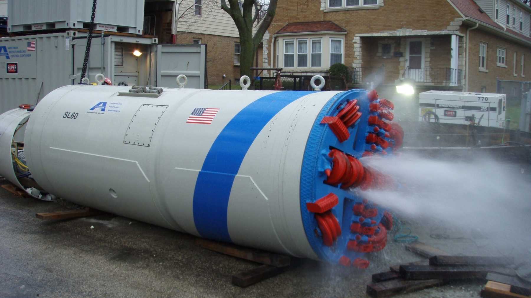 Three tunnel boring machines pushed 42-, 48- and 66-inch sewer pipes beneath a Nebraska creek, 525 feet of tunneling through wet clay held open by slurry pressure, so a 90-inch steel pipe hanging in the open air over the water could come down