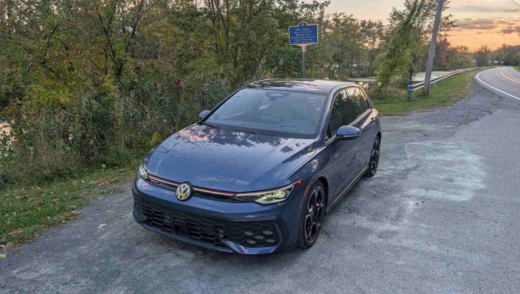 A high angle front 3/4 view of a A side view of a blue 2026 Volkswagen Golf GTI